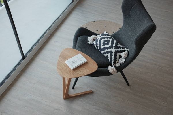 Odkládací stolek TRIANGLE z dubového masivu s knihou v prosvětleném interiéru